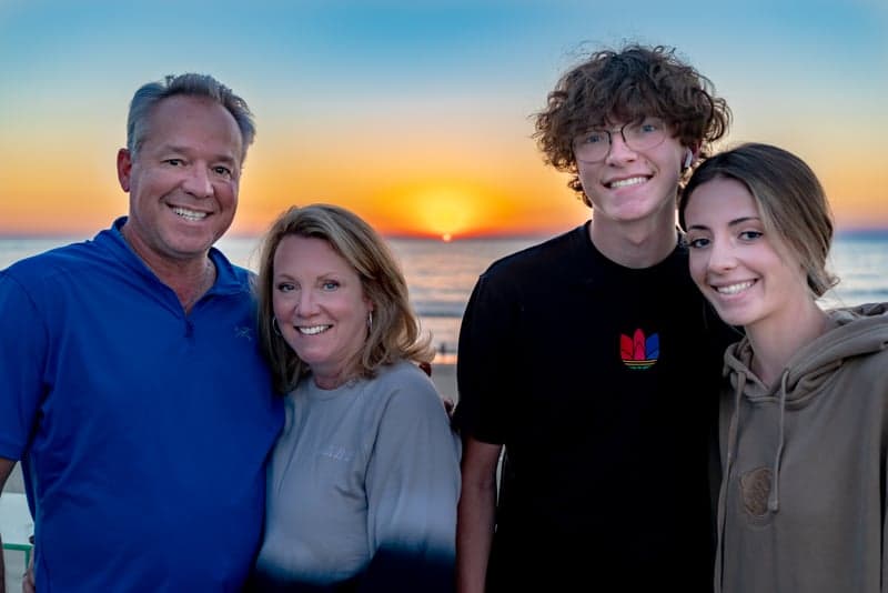 Silhouetted figures watching a vibrant sunset from a mountain pass