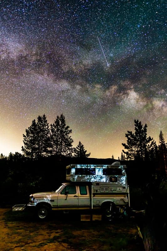 A truck parked under a brilliant starry sky with the Milky Way overhead